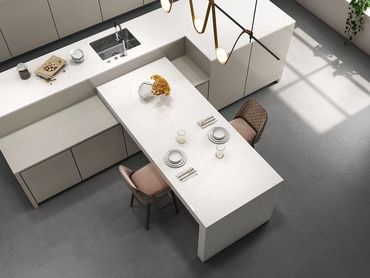Modern kitchen island with two chairs and table settings under stylish lighting.