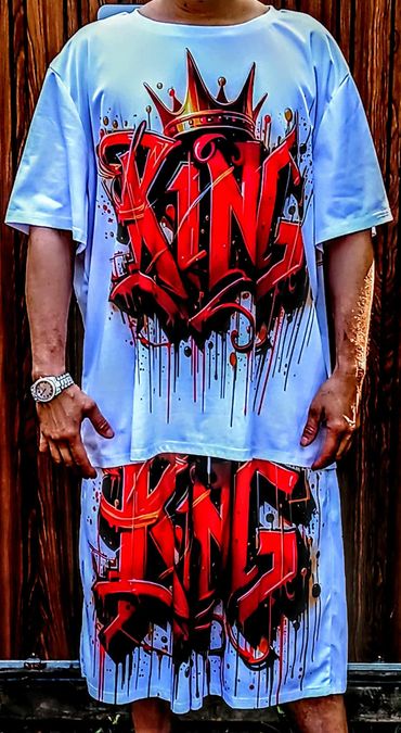 Person wearing a white outfit with bold red graffiti-style "KING" text and crown design.