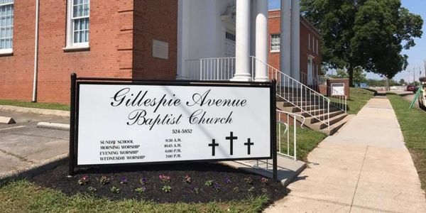 Sign for Gillespie Avenue Baptist Church outside a brick building.