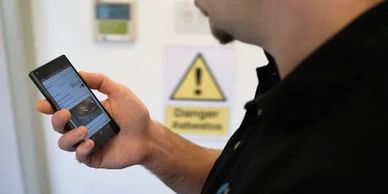 asbestos surveyor using Tracker Mobile on a smartphone to gather asbestos data