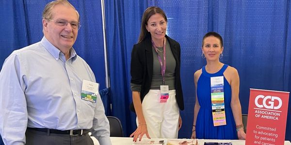 Three people standing at a convention table for CGD