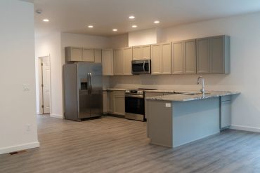 Modern kitchen with gray cabinets and stainless steel appliances.