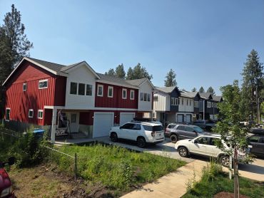 Row of colorful townhouses with cars parked outside on a sunny day.