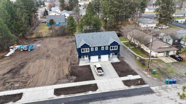 Newly built blue duplex with a white truck in driveway.