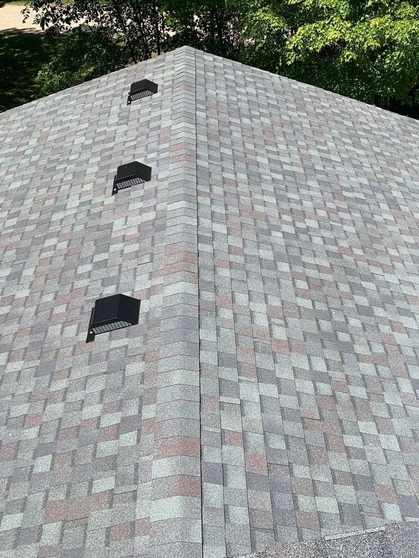 Newly installed shingle roof with ventilation vents on a sunny day.