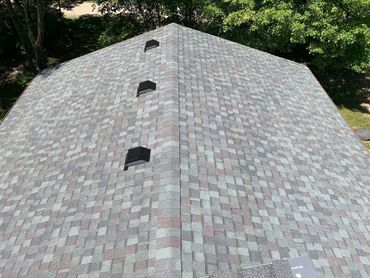 Newly installed shingle roof with ventilation vents on a sunny day.