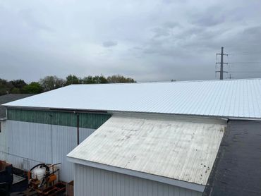 A metal roof on an industrial building under a cloudy sky.