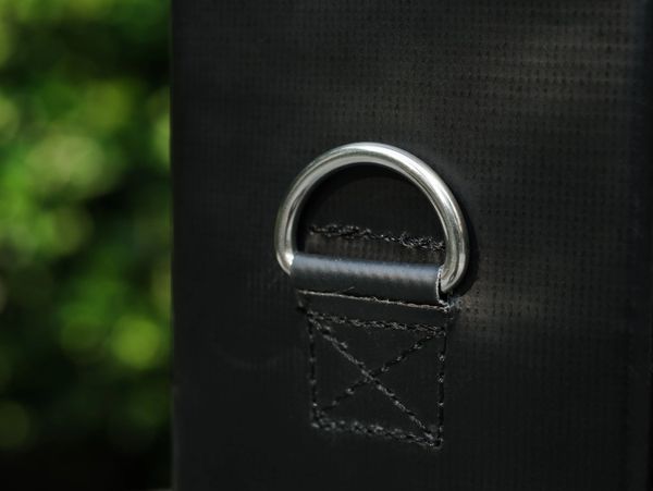 Metal D-ring attached to black fabric with stitching.