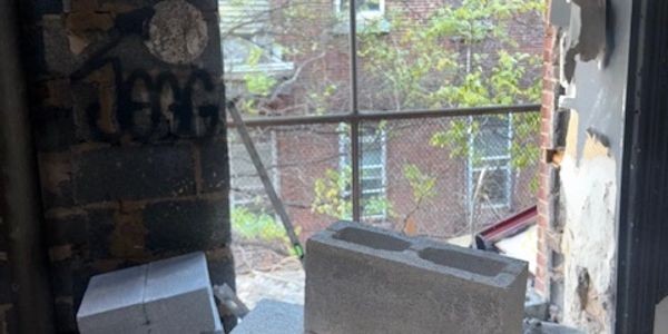 A window view with concrete blocks and a fence outside.