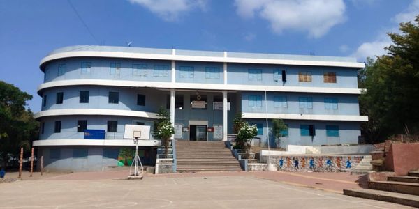 A modern three-story school building with a basketball hoop in front.