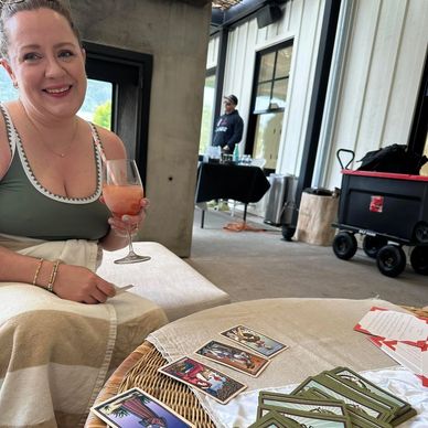Woman enjoying a drink while tarot cards lay on the table.