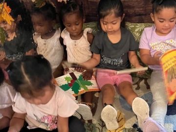 Children read a book in the book area during free play.