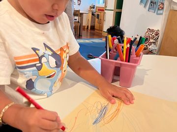 Two year old drawing on manilla paper with colored pencil.