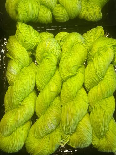 Bright neon yellow-green yarn skeins arranged closely together.