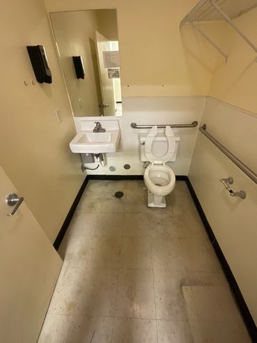Small, basic accessible restroom with sink, toilet, and grab bars.