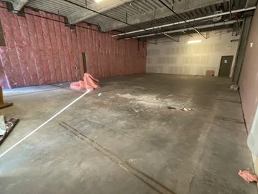 An empty industrial space under construction with exposed insulation and concrete floor.