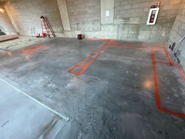 Concrete floor with orange markings in an unfinished construction site.