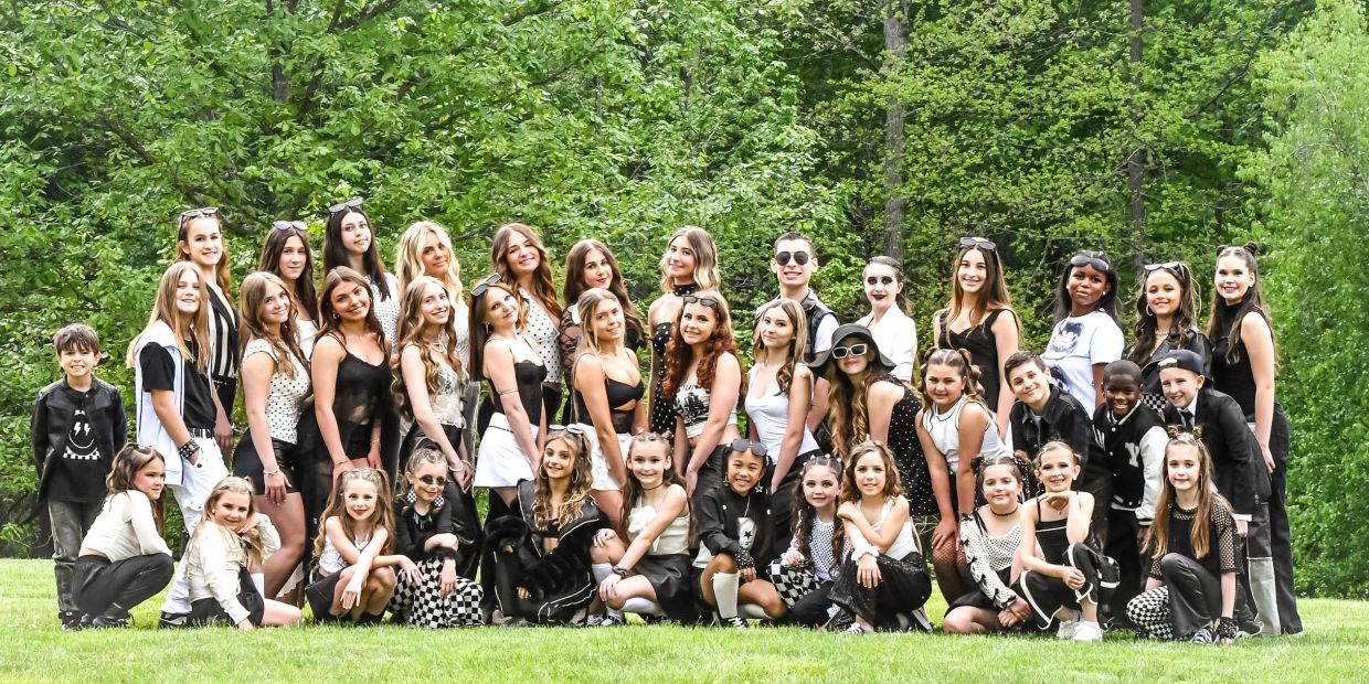 Large group of young people posing outdoors in coordinated black and white outfits.