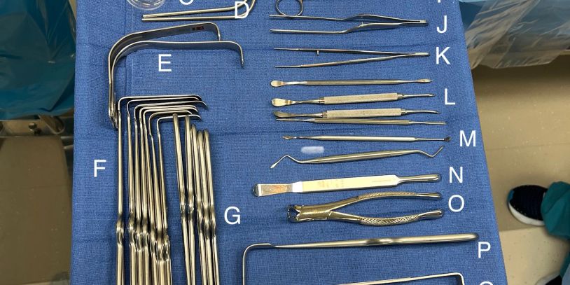 Surgical instruments laid out on a blue cloth with labels.