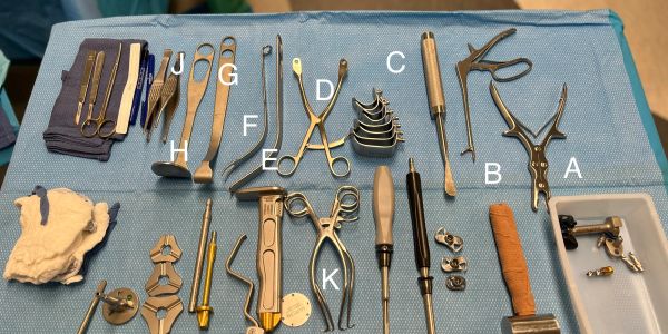 Surgical tools labeled A-K on a blue cloth.