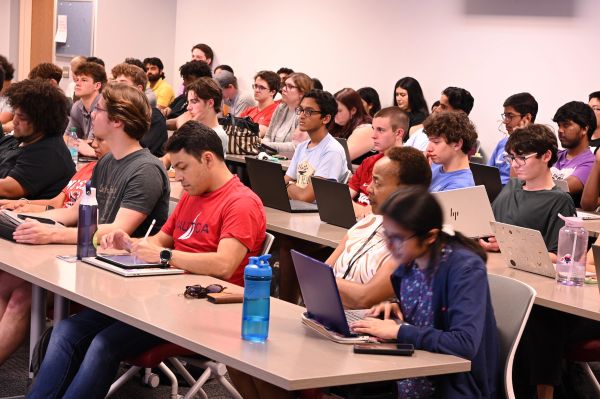 Students engaged in a lecture with laptops and notebooks.
