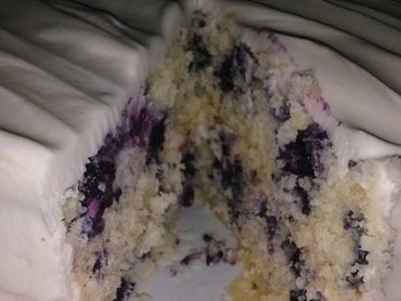 A partially eaten blueberry cake with white frosting.