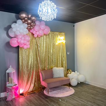 Birthday photo setup with balloons, gold backdrop, and pink couch.