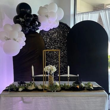 Elegant black and white decorated table with balloons and floral centerpiece.