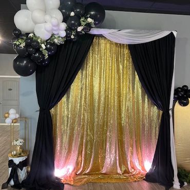 Elegant black and gold backdrop with white and black balloon decor for a celebration.