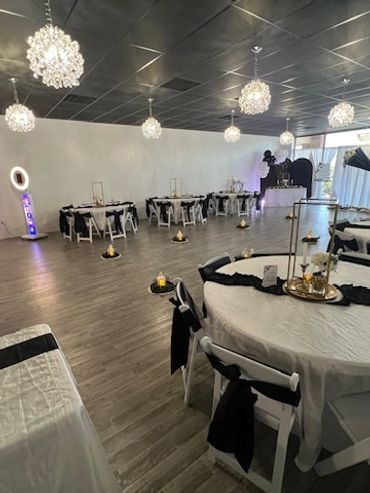 Elegant event space with black and white decor and crystal chandeliers.
