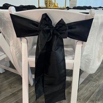 Satin black chair sash tied onto the back of a white resin banquet chair at Suite Events venue.