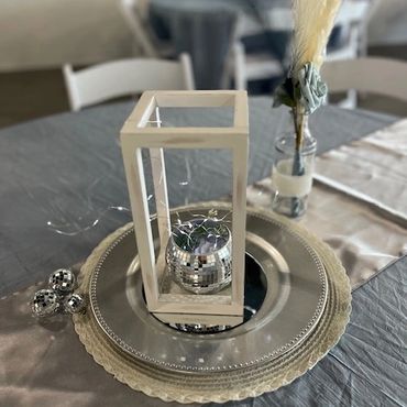 Table centerpieces with chargers, lights, and disco balls.