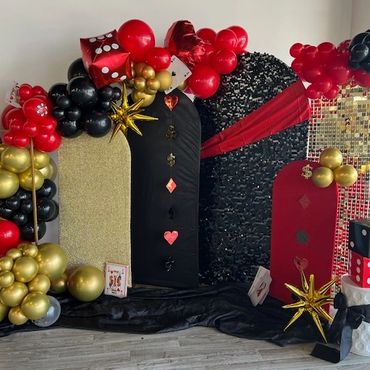 Poker themed birthday party decor in red, black, gold, and white - showing backdrop area with arches