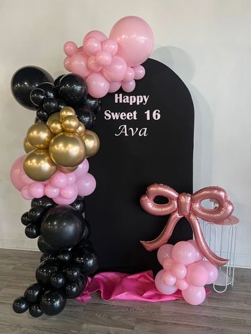 Sweet 16 birthday decoration with pink, black, and gold balloons.