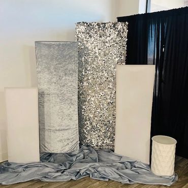 Decorative silver and white panels with fabric and textured vase on wooden floor.