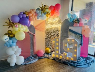Colorful balloon arch and illuminated '19' for a birthday celebration.
