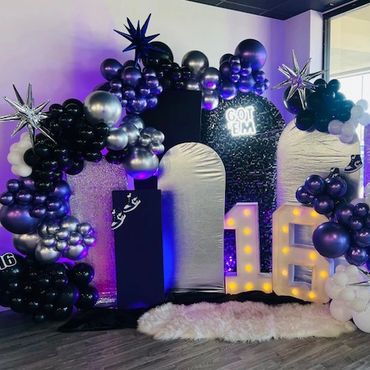16th birthday party decor in purple, black, and silver with uplighting.