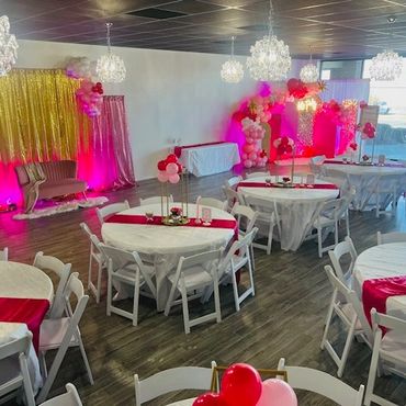 A bright, elegant event space with round tables and pink-red decorations.