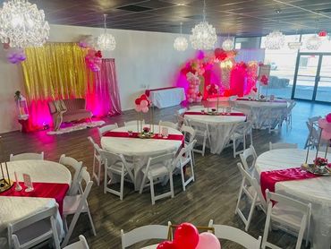 A bright, elegant event space with round tables and pink-red decorations.