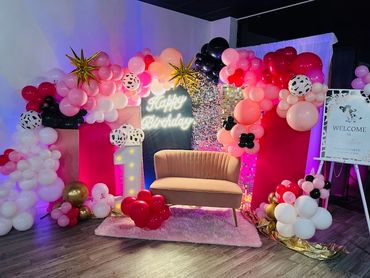 Colorful balloon decorations with a 'Happy Birthday' sign and a cozy sofa setup.