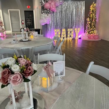 Elegant baby shower setup with floral centerpieces and balloon decorations.