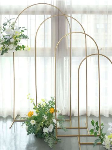 Elegant gold arch frames decorated with white and yellow flowers for events.