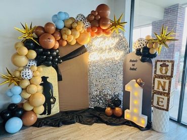 Colorful balloon arch and decorations for a cowboy-themed first birthday party.