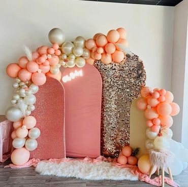 Elegant pink, peachy pink, and ivory backdrop setup for a baby shower.