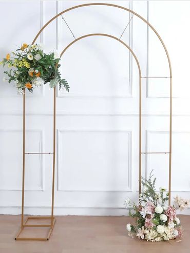 Minimalist gold arch decorated with fresh flowers on white background.