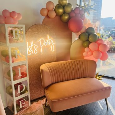 Pink velvet sofa with arches and balloon garland for bridal shower.