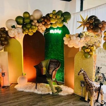 Elegant jungle-themed baby shower setup with balloons, a chair, and animal decorations.