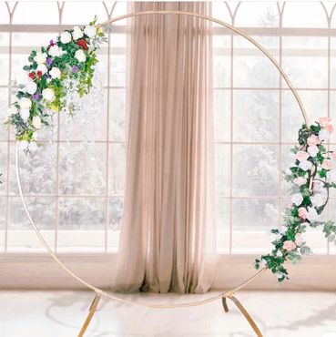 Circular floral arch decorated with white and pink flowers against a window.