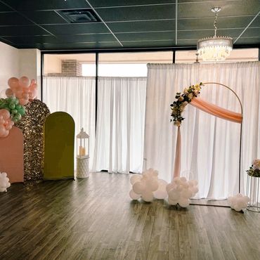 Elegant wedding setup with floral arch and balloons.