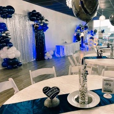 Elegant event setup with blue and white decor, balloons, and themed centerpieces.